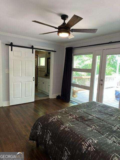 bedroom featuring dark hardwood / wood-style floors, ornamental molding, access to exterior, ceiling fan, and a barn door