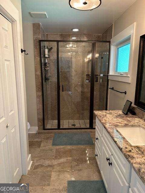 bathroom with a shower with door, vanity, and toilet