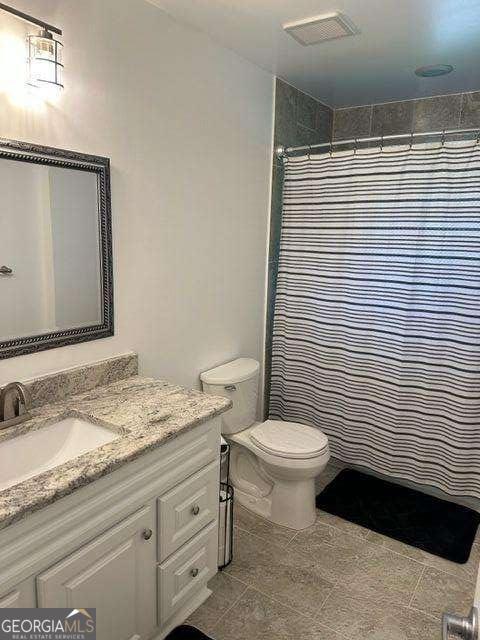 bathroom with toilet, vanity, and walk in shower