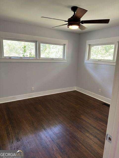 spare room with dark hardwood / wood-style flooring, ceiling fan, and a wealth of natural light