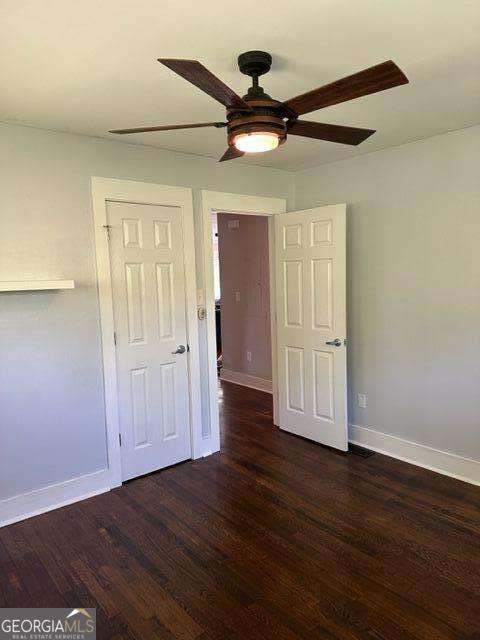 empty room featuring dark wood-type flooring and ceiling fan