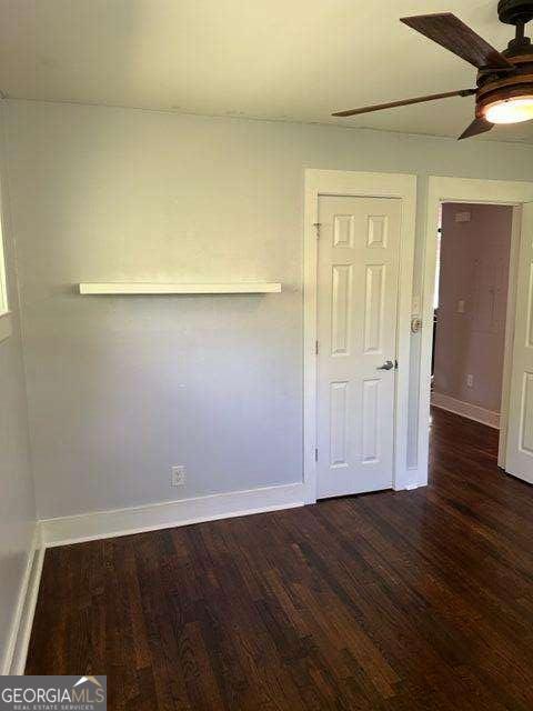 empty room with dark hardwood / wood-style flooring and ceiling fan