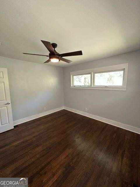 empty room with dark hardwood / wood-style floors and ceiling fan