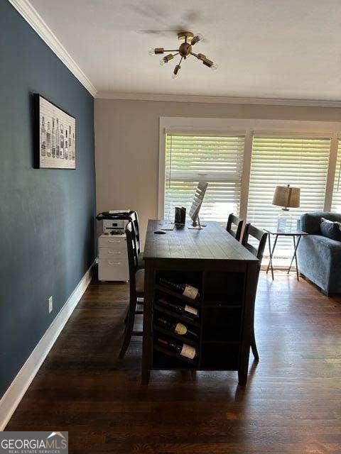 dining space featuring dark wood-type flooring and crown molding