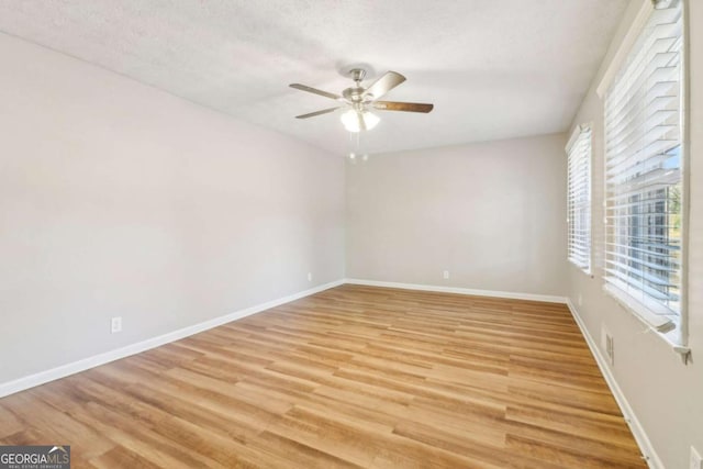 empty room with a textured ceiling, light hardwood / wood-style floors, and ceiling fan