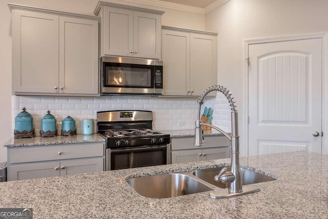 kitchen featuring stainless steel appliances, ornamental molding, sink, and light stone counters