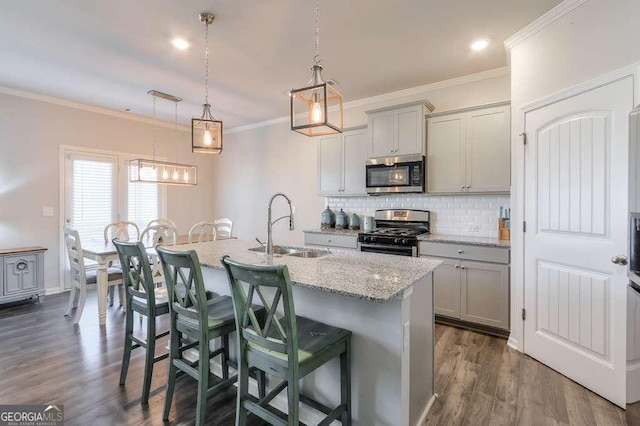 kitchen featuring sink, a breakfast bar, range with gas stovetop, an island with sink, and decorative light fixtures