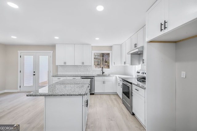 kitchen featuring a kitchen island, appliances with stainless steel finishes, white cabinetry, sink, and light stone countertops