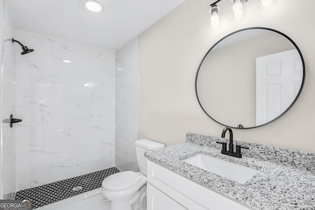 bathroom featuring vanity, toilet, and a tile shower