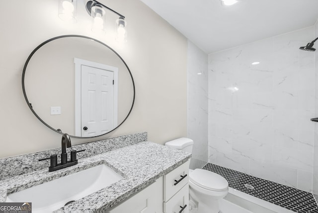 bathroom featuring vanity, a tile shower, and toilet