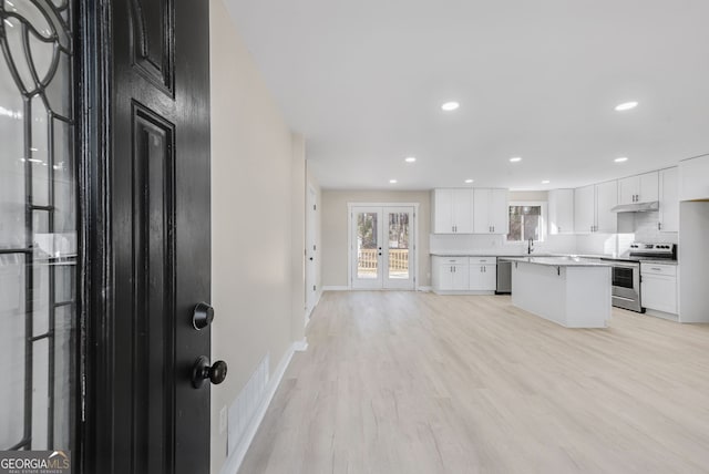 kitchen with a kitchen island, sink, white cabinets, light hardwood / wood-style floors, and stainless steel appliances