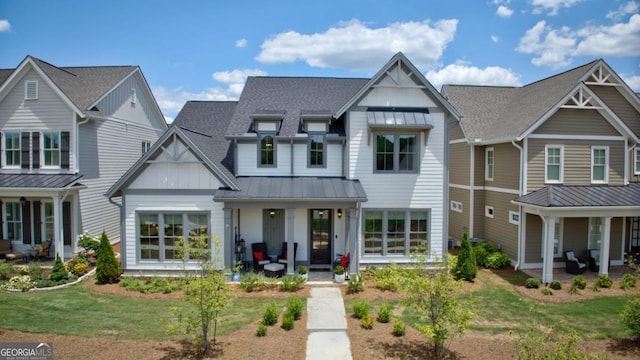 view of front of property featuring board and batten siding, a standing seam roof, covered porch, metal roof, and a front lawn