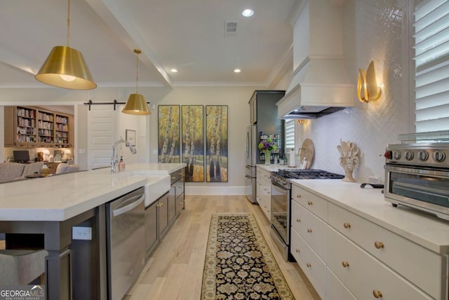 kitchen featuring light wood-style floors, visible vents, a sink, stainless steel appliances, and custom range hood