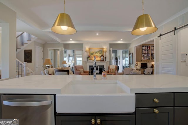 kitchen featuring light stone counters, decorative light fixtures, stainless steel dishwasher, and a barn door