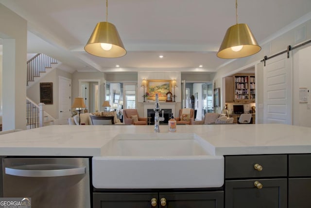 kitchen featuring a barn door, dishwasher, a sink, open floor plan, and a fireplace
