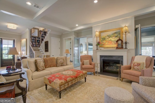 living area with a glass covered fireplace, stairs, visible vents, and a wealth of natural light