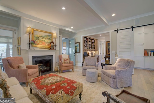 living area featuring a fireplace with flush hearth, recessed lighting, a barn door, and light wood finished floors