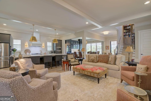 living room with light hardwood / wood-style flooring, plenty of natural light, ornamental molding, and beamed ceiling