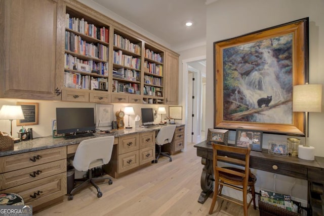 office space featuring crown molding, built in desk, and light hardwood / wood-style floors