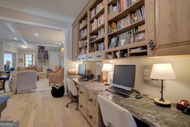 office space with ornamental molding, built in desk, and light hardwood / wood-style floors