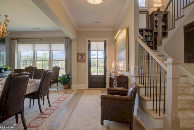 entryway with crown molding, wood finished floors, visible vents, and stairway