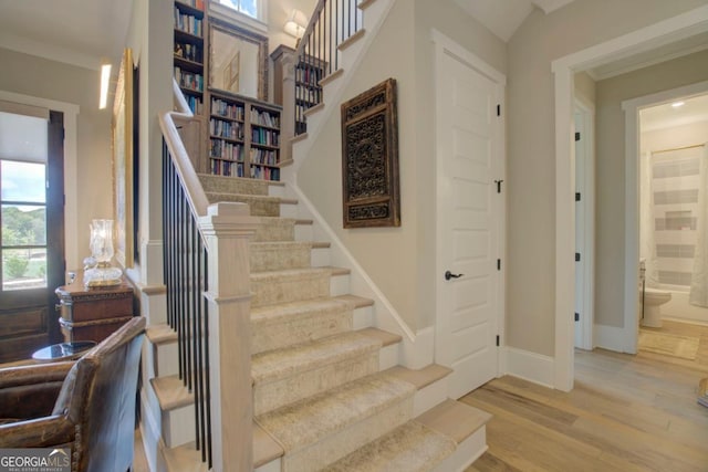 stairs with hardwood / wood-style flooring and crown molding