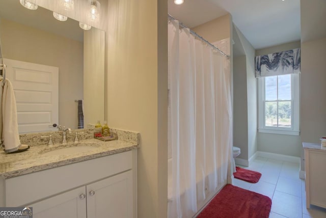 full bathroom featuring toilet, vanity, baseboards, and tile patterned flooring