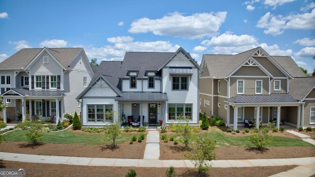 view of front of house featuring a standing seam roof, covered porch, metal roof, a front yard, and a shingled roof