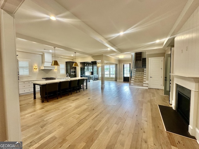 living area featuring recessed lighting, a fireplace, light wood-style flooring, and stairs