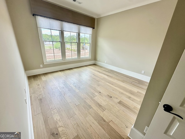 spare room featuring wood-type flooring, baseboards, and visible vents