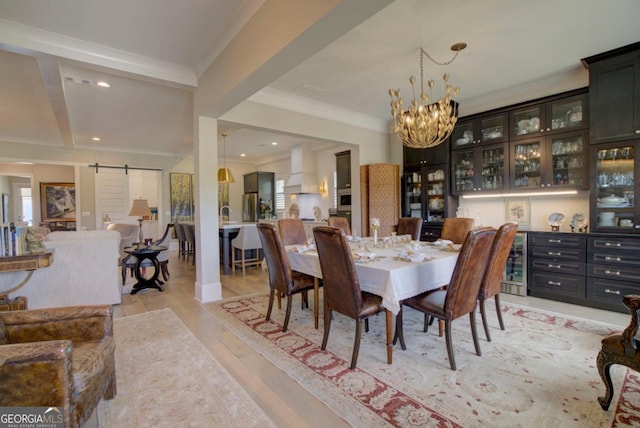 dining area featuring an inviting chandelier, ornamental molding, a barn door, and light wood-type flooring