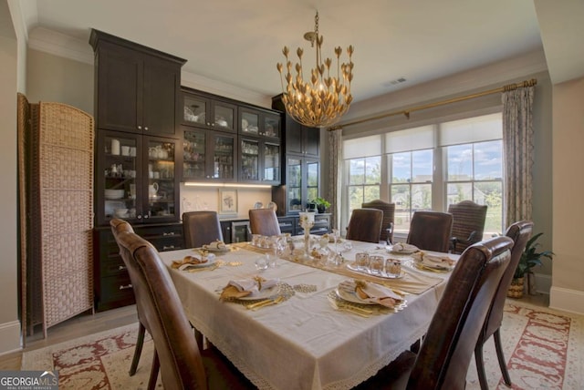 dining room with crown molding, light wood-type flooring, and a notable chandelier