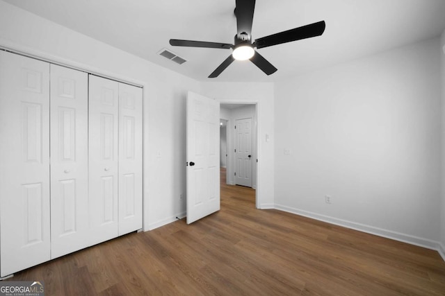 unfurnished bedroom with wood-type flooring, ceiling fan, and a closet