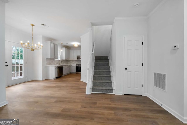 interior space with an inviting chandelier, ornamental molding, sink, and hardwood / wood-style floors