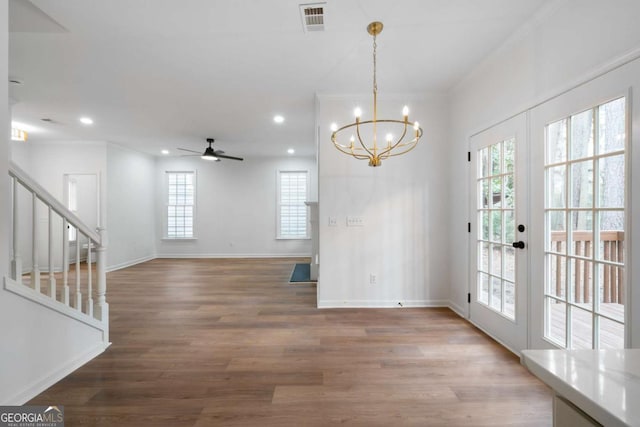 unfurnished dining area featuring hardwood / wood-style flooring, ceiling fan with notable chandelier, ornamental molding, and french doors