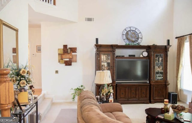 carpeted living room featuring a healthy amount of sunlight and a high ceiling