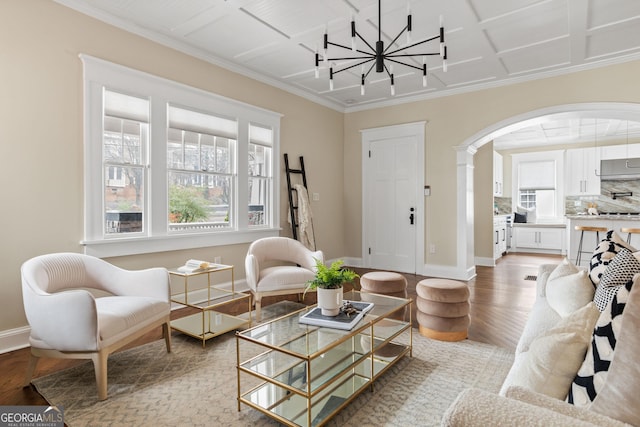 living room with baseboards, coffered ceiling, an inviting chandelier, arched walkways, and light wood-style floors