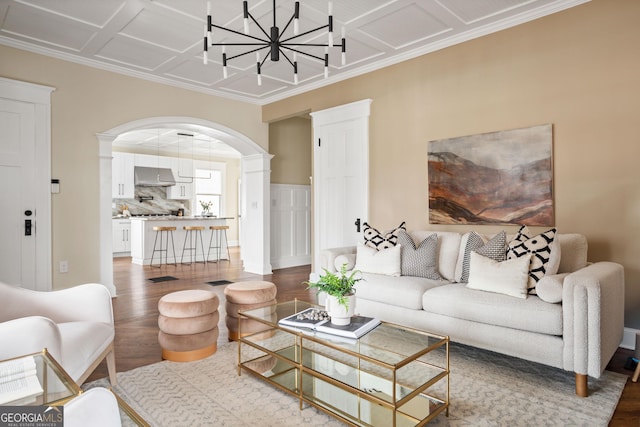 living room featuring arched walkways, a notable chandelier, ornate columns, and wood finished floors