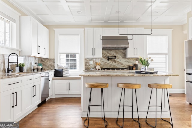 kitchen with light wood-style flooring, a sink, appliances with stainless steel finishes, a breakfast bar area, and extractor fan