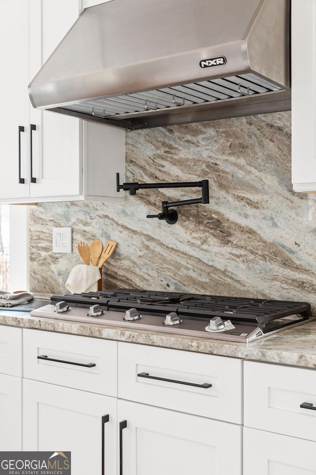 kitchen with backsplash, range hood, and white cabinets