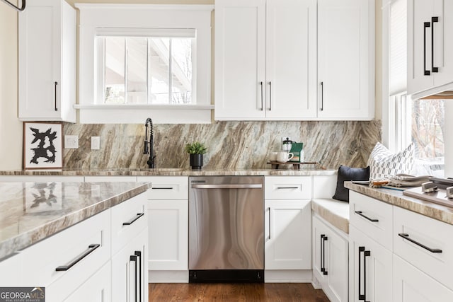 kitchen with tasteful backsplash, stainless steel dishwasher, and white cabinetry