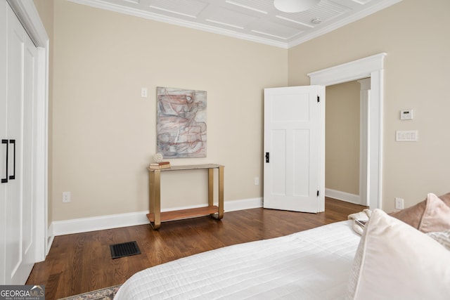 bedroom with visible vents, baseboards, wood finished floors, and ornamental molding