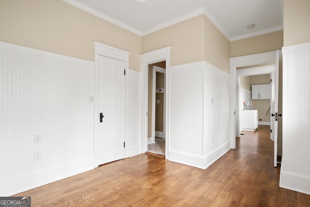 unfurnished bedroom featuring wainscoting, crown molding, and wood finished floors