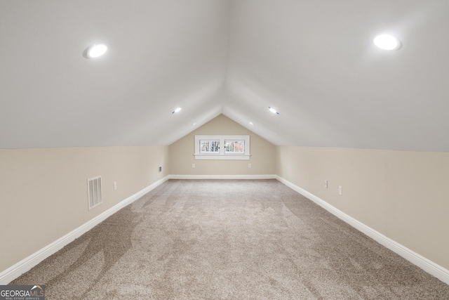 additional living space featuring visible vents, lofted ceiling, carpet, and baseboards