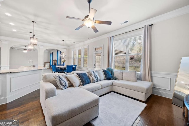 living room featuring ceiling fan, ornamental molding, dark hardwood / wood-style flooring, and sink