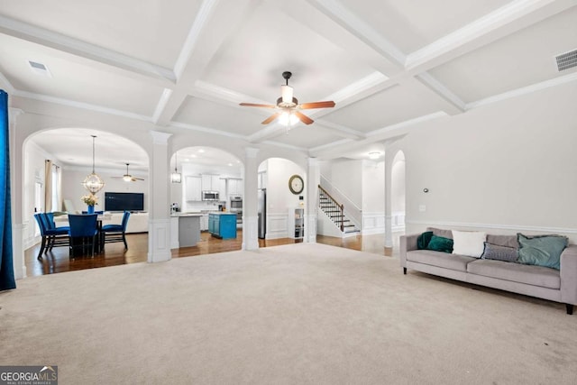 living room featuring hardwood / wood-style floors, ceiling fan with notable chandelier, coffered ceiling, crown molding, and beam ceiling