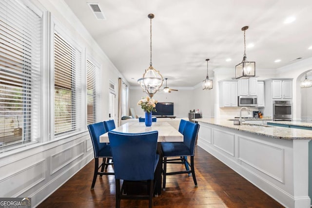 dining area featuring dark wood-type flooring, crown molding, and sink