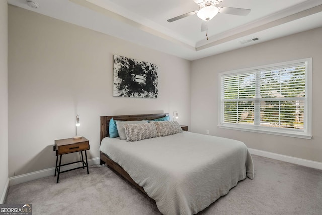 carpeted bedroom with a tray ceiling and ceiling fan