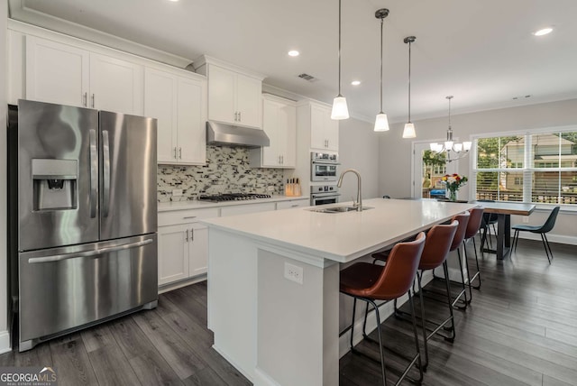 kitchen featuring appliances with stainless steel finishes, pendant lighting, white cabinetry, sink, and a kitchen island with sink