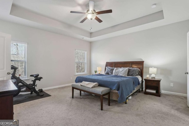 carpeted bedroom featuring a raised ceiling and ceiling fan